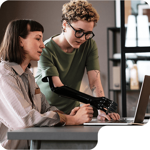 Two professionals smiling and working together on a tablet and laptop
